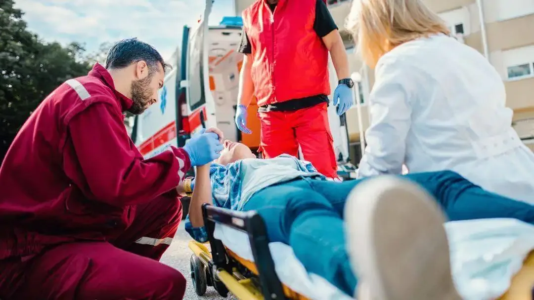 Paramedics attending to a patient on a stretcher beside an ambulance