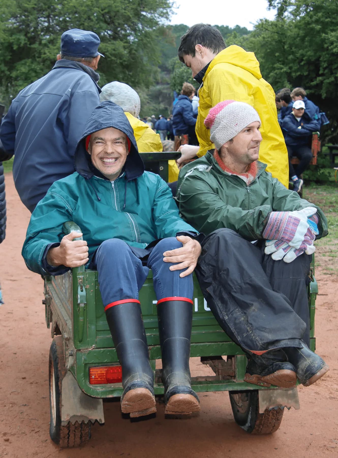 Two Camphill residents sitting side by side on the back of a farm trailer, smiling on a village outing